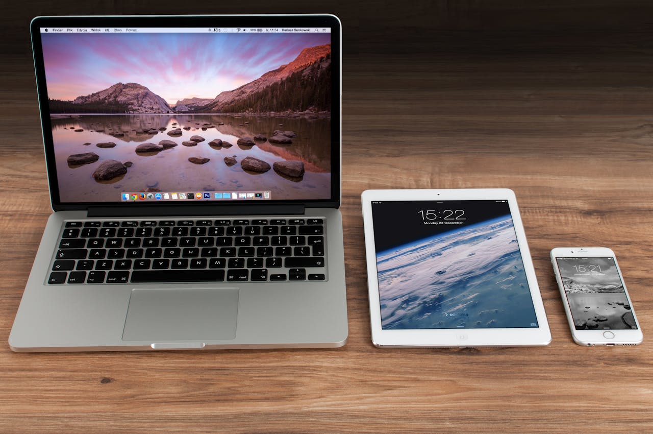 creative Modern workspace showcasing Apple laptop, tablet, and smartphone on a wooden desk.
